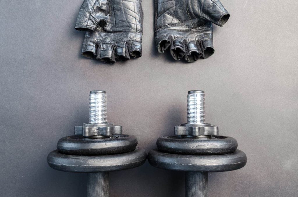 Musculation avec ou sans gants : des haltères et des gants au sol