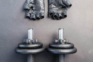 Musculation avec ou sans gants : des haltères et des gants au sol